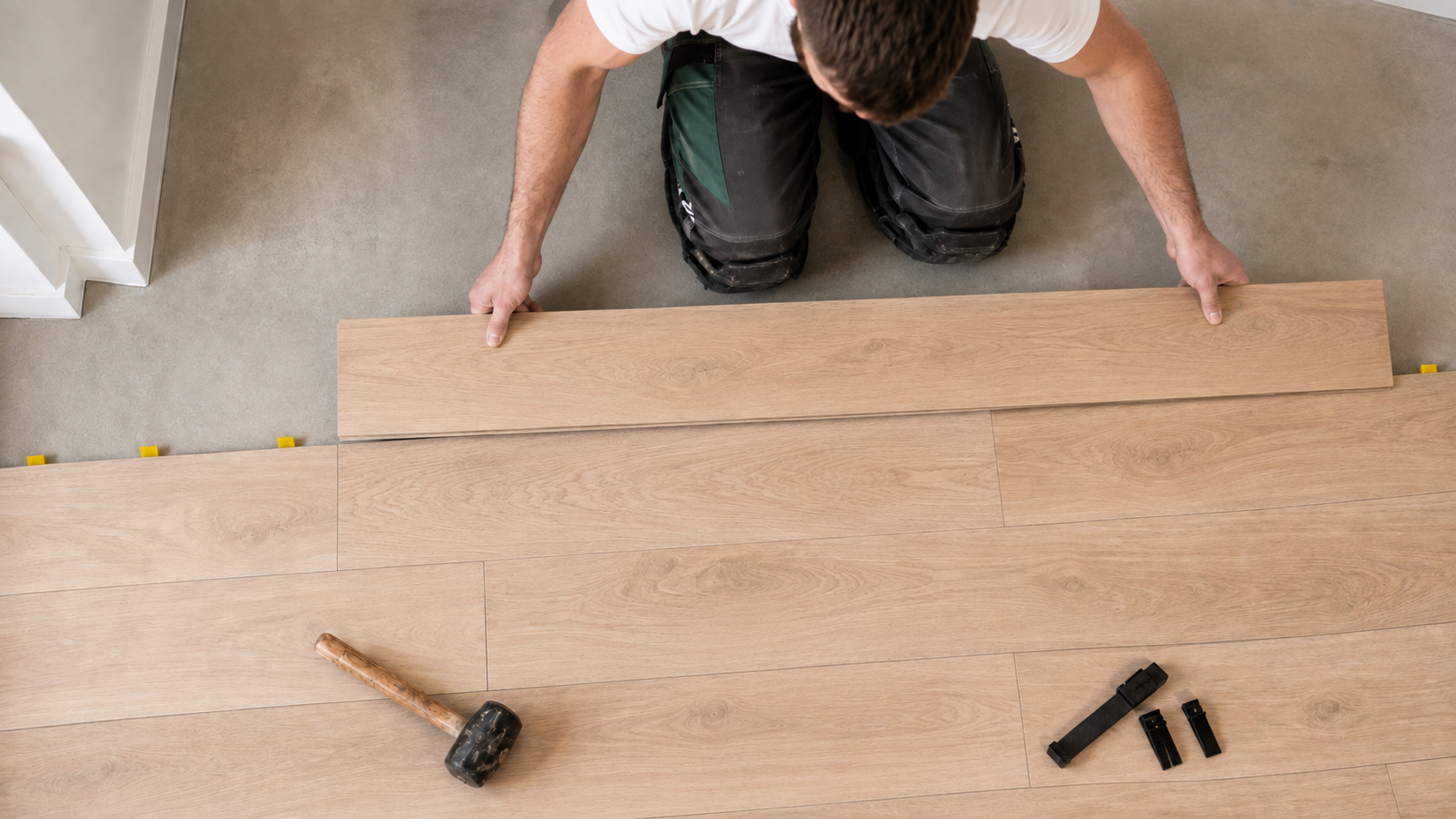 Kovi fitter laying an engineered oak plank across a prepped subfloor